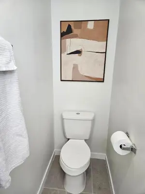 a bathroom with a toilet and a painting on the wall at Clintonville Charmer - Central, Arcade, Selfie Wall in Columbus