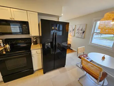 a kitchen with a black refrigerator and a table at Clintonville Charmer - Central, Arcade, Selfie Wall in Columbus