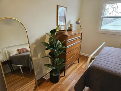a bedroom with a dresser and a mirror and a plant at Clintonville Charmer - Central, Arcade, Selfie Wall in Columbus