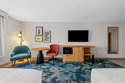 a hotel room with a desk and two chairs and a television at Hampton Inn Mt. Vernon Oh in Academia