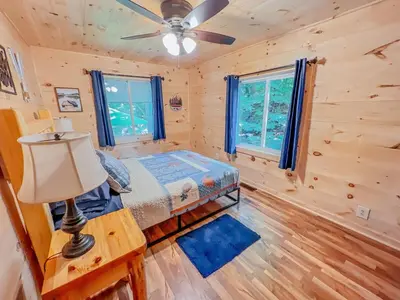 a bedroom in a log cabin with a bed and a lamp at Lake Life, Hocking Hills, Hot Tub, Fireplace, Pond in Rockbridge