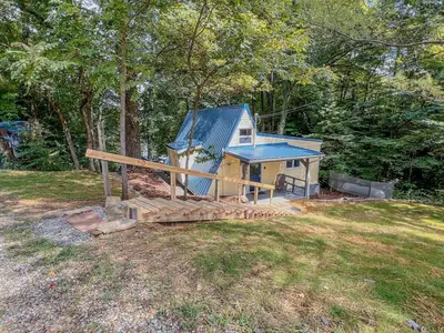a small house with a blue roof in a yard at Lake Life, Hocking Hills, Hot Tub, Fireplace, Pond in Rockbridge