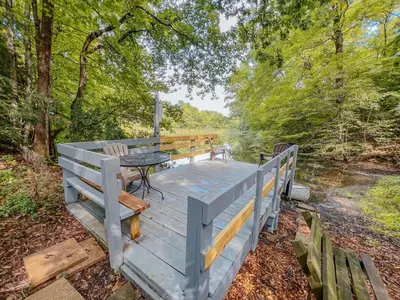 a wooden deck with a table and a bench on it at Lake Life, Hocking Hills, Hot Tub, Fireplace, Pond in Rockbridge