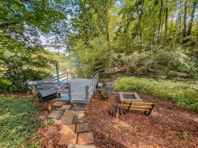 a house in the woods with a picnic table and benches at Lake Life, Hocking Hills, Hot Tub, Fireplace, Pond in Rockbridge