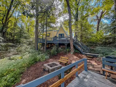 a house in the woods with a deck and stairs at Lake Life, Hocking Hills, Hot Tub, Fireplace, Pond in Rockbridge