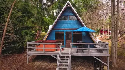 a blue cabin in the woods with a ladder at Whispering Waters, Hocking Hills, Hot Tub, Pond in Rockbridge