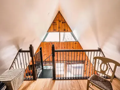 an attic room with a large window in a building at Whispering Waters, Hocking Hills, Hot Tub, Pond in Rockbridge