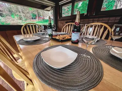 a table with a plate of food and two bottles of wine at Edgewater Escape, Hocking Hills, Hot Tub, Pond in Rockbridge