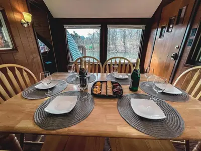 a wooden table with plates and wine glasses on it at Edgewater Escape, Hocking Hills, Hot Tub, Pond in Rockbridge