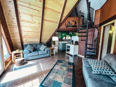 a living room with wooden walls and a spiral staircase at Edgewater Escape, Hocking Hills, Hot Tub, Pond in Rockbridge