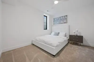 a white bedroom with a bed and a night stand at Jungle House Luxury Homes - Columbus Downtown Short North - Near Convention Center & Nationwide Arena - Sleeps up to 15 - Free Parking - Over 5,800 Five Stars in Columbus