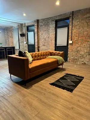 a brown couch in a room with a brick wall at Jungle House Luxury Stays - Columbus Downtown Short North in Columbus