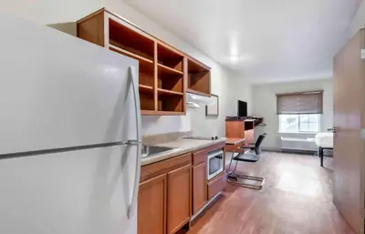 a kitchen with a white refrigerator and wooden cabinets at Extended Stay America Select Suites - Dayton - Miamisburg in Dayton