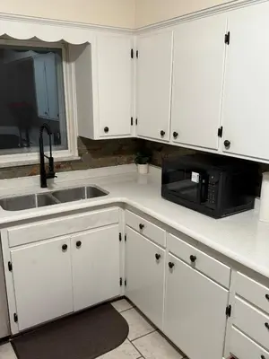 a kitchen with white cabinets and a sink and a microwave at The Gather Grove in Toledo