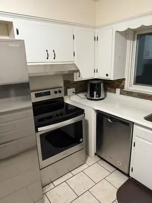 a kitchen with white cabinets and a stove top oven at The Gather Grove in Toledo