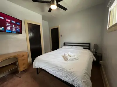 a bedroom with a bed with white sheets and a ceiling fan at Great Room near Cleveland airport in Cleveland