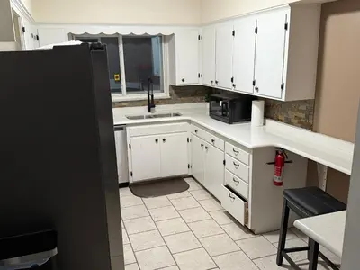 a kitchen with white cabinets and a black refrigerator at The Unity Hub in Toledo