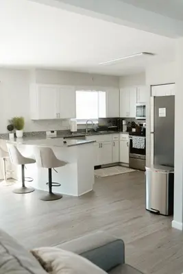 a kitchen with white cabinets and a table and a refrigerator at Mid Ohio Comfort 10 Minutes From Snow Trails in Lexington