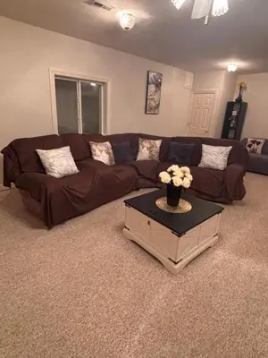 a living room with a brown couch and a table with flowers at Downstairs oasis