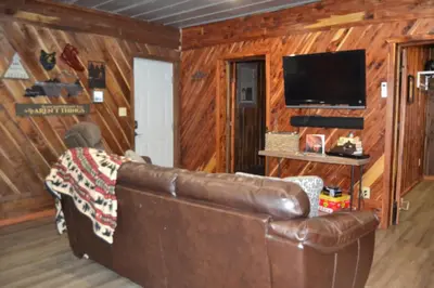 a living room with a leather couch and a flat screen tv at Restful River Cabin, Red River Gorge, KY, River Access & Views in Stanton