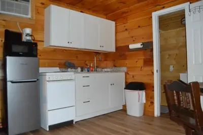 a kitchen with white appliances and wooden walls at Campfire Cabin, Red River Gorge, KY, River Access & Views in Stanton