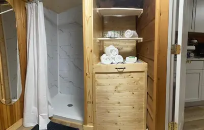 a bathroom with a shower and a wooden cabinet with towels at Sleepy Bear Cabin, Red River Gorge, KY, River Access & Views in Stanton