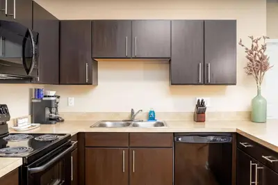 a kitchen with wooden cabinets and a stainless steel sink at The New Albany Perch Top Floor Pet-Friendly! in Westerville