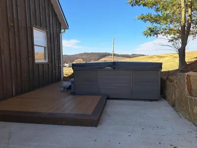 a hot tub on a deck next to a building at Peaceful Valley Retreat in Sugarcreek