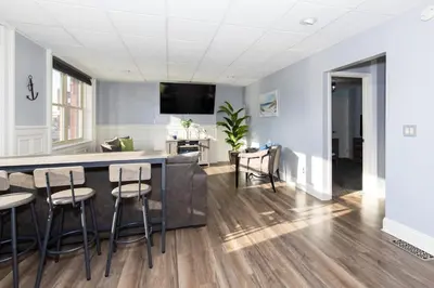 a kitchen and living room with a bar and stools at Upgraded Downtown Apartment Sleeps 5 in Sandusky