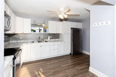 a kitchen with white cabinets and a ceiling fan at Upgraded Downtown Apartment Sleeps 5 in Sandusky
