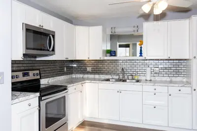 a white kitchen with a sink and a microwave at Upgraded Downtown Apartment Sleeps 5 in Sandusky