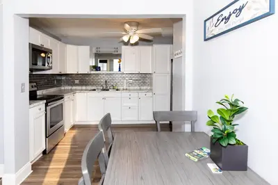 a kitchen with white cabinets and a table and chairs at Upgraded Downtown Apartment Sleeps 5 in Sandusky