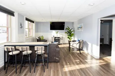 a kitchen and living room with a bar and stools at Upgraded Downtown Apartment Sleeps 5 in Sandusky