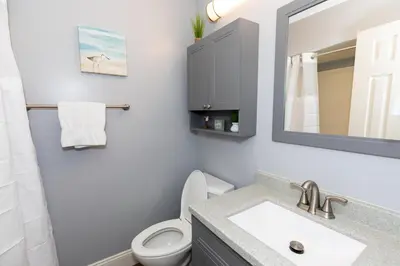 a bathroom with a sink and a toilet and a mirror at Upgraded Downtown Apartment Sleeps 5 in Sandusky