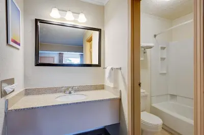 a bathroom with a sink and a toilet and a mirror at Days Inn by Wyndham Fairmont in Fairmont