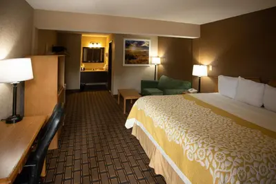 a hotel room with a large bed and a chair at Days Inn by Wyndham Fairmont in Fairmont