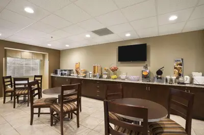 a waiting room with tables and chairs and a flat screen tv at Microtel Inn & Suites by Wyndham Cambridge in Cambridge