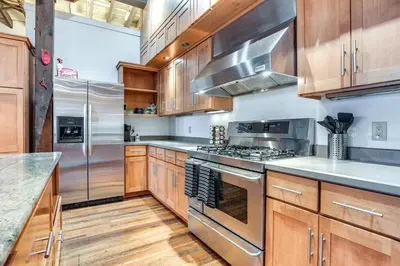a kitchen with wooden cabinets and stainless steel appliances at Less Than 1 Mi to Wittenberg Eclectic Loft with Parking! in Springfield