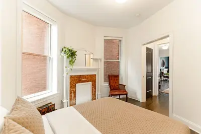 a white bedroom with a bed and a fireplace at Lux Washington-Park Rooftop Patio-Free Parking in Cincinnati