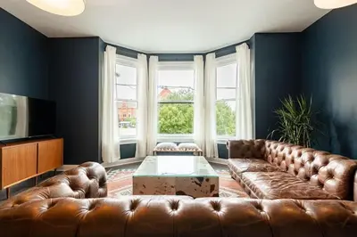 a living room with a brown leather couch and a table at Lux Washington-Park Rooftop Patio-Free Parking in Cincinnati