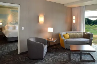 a hotel room with a bed and a couch and a chair at Courtyard by Marriott Youngstown Canfield in Canfield