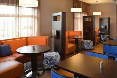 a waiting room with tables and orange chairs at Courtyard by Marriott Youngstown Canfield in Canfield