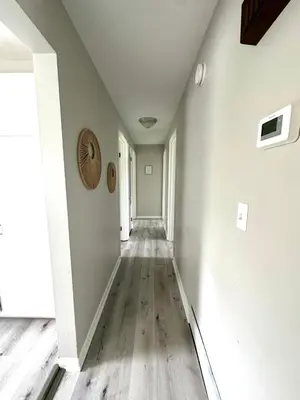 an empty hallway with white walls and wooden floors at Hot tub bubbles on Butler in Mason
