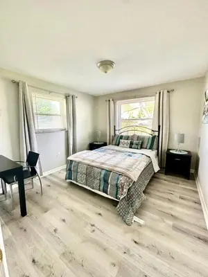 a bedroom with a bed and a desk and two windows at Hot tub bubbles on Butler in Mason