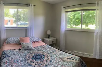a bedroom with a bed and two windows at Lovely Retreat Backyard With Deck and entertain room in Mason