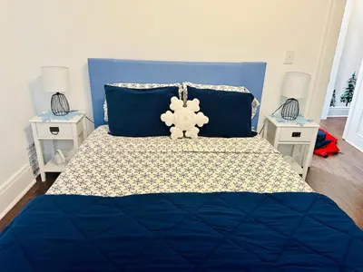 a teddy bear sitting on top of a blue bed at Holly Jolly Historic Home Where Its Always XMAS in Hamilton