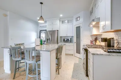 a kitchen with white cabinets and a island with bar stools at 4 Mi to Lake Logan Hocking Hills Apartment in Logan