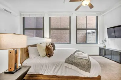 a bedroom with a bed with a ceiling fan and windows at Lofts on E 4th, WALK TO CAVS, Sleeps 6 in Cleveland