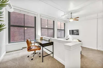 an office with a desk and a chair and windows at Lofts on E 4th, WALK TO CAVS, Sleeps 6 in Cleveland