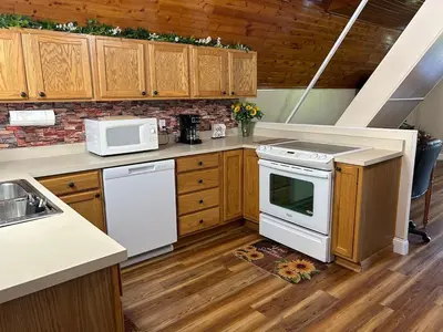 a kitchen with white appliances and wooden cabinets at Cherokee Cabin-Cave Run Lake and Cliff Views-Red River Gorge in Big Woods